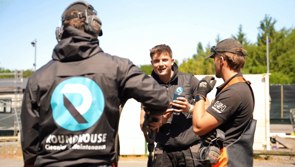 Roundhouse UK cleaning and maintenance team discussing work on-site, wearing branded uniforms and safety gear.