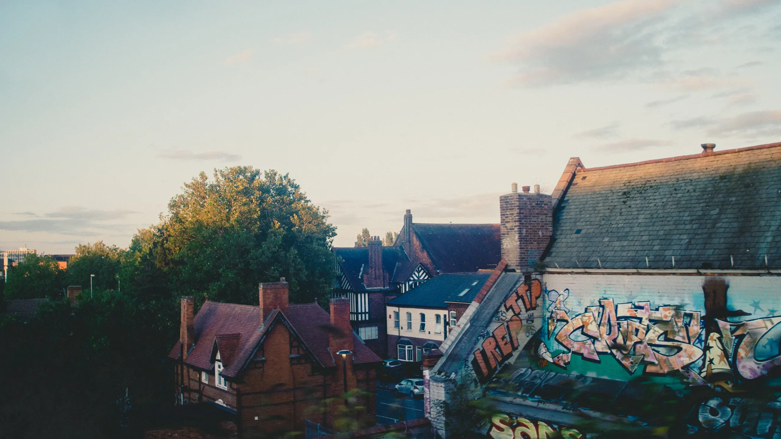 Graffiti on the side wall of a tiled-roof building in a residential area.